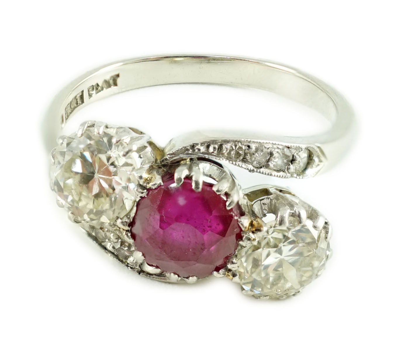 An 18ct white gold and platinum, two stone diamond and single stone synthetic? ruby set crossover ring, with diamond set shoulders